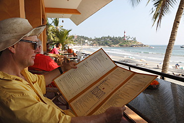 Tourist reading the menu of a cafe on Lighthouse Beach, Kovalam, Malabarian Coast, Malabar, Kerala state, India, Asia