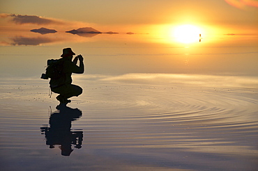 Tourist taking pictures of the sunset at the Salar de Uyuni, Uyuni, Bolivia, South America