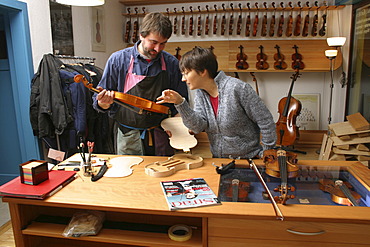 Violin-maker (luthier) with a customer in his shop