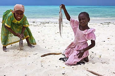 Children beating an octopus with sticks to make it edible, Jambiani, Zanzibar, Tanzania, Africa