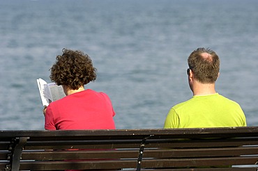 Couple sitting on bench at lake