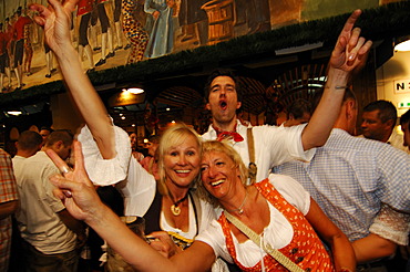 Women wearing traditional dress, called a Dirndl, dancing in the Beer Tent at the Oktoberfest Beer Festival or Wies\'n in Munich, Bavaria, Germany, Europe