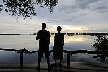 Tourists sitting on the terrace of a lodge in the evening, Guma Lagoon, Guma Lagoon, Okavango Delta, Botswana, Africa