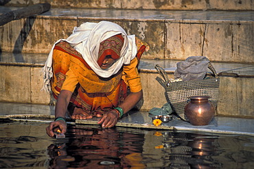 Woman during a morning prayer or puja, putting oil lamp on the Ganges River, ghats, Kashi, Varanasi or Benares, Uttar Pradesh, North India, India, Asia