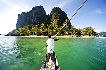 Boatsman in a traditional outrigger boat approaching Inabuyutan Island, Bacuit Archipelago, El Nido, Palawan, Philippines, Asia