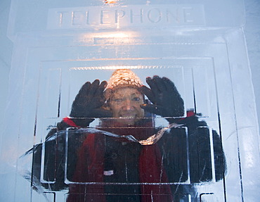 Woman in a telephone booth made of ice, ice hotel of Jukkasjaervi, Lappland, Northern Sweden