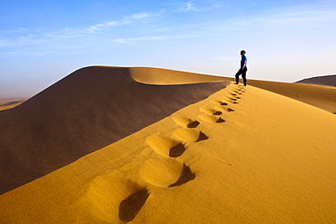 Woman walking in the dunes, Erg Chegaga region, Sahara desert near Mhamid, Morocco, Africa