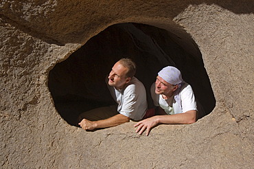 Man looking through a hole in the rock, Jebel Uweinat, Jabal al Awaynat, Libya