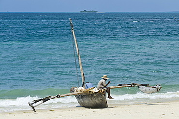 Fisherman sitting on a Ngalawa, a traditional double-outrigger canoe, Zanzibar, Tanzania, Africa