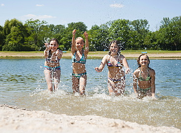 Group of girls splashing each other and playing in a lake