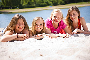 Group of girls sitting on the beach of a lake