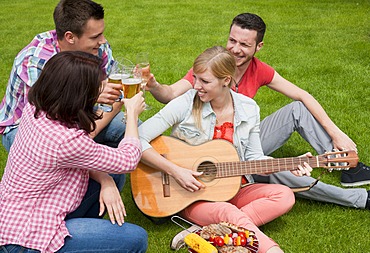 Group of young people at a barbecue with beer and a guitar in the garden