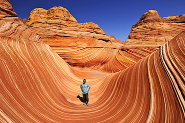 Tourist in The Wave, banded eroded Navajo sandstone rocks with Liesegang Bands, Liesegangen Rings, or Liesegang Rings, North Coyote Buttes, Paria Canyon, Vermillion Cliffs National Monument, Arizona, Utah, USA