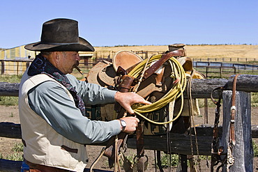 Cowboy preparing saddle, wildwest, Oregon, USA