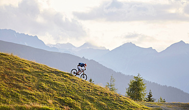 Mountain biker on the descent on a fire road, Mutterer Alm near Innsbruck, Northern chain of the Alps behind, Tyrol, Austria, Europe