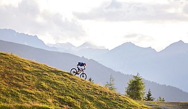 Mountain biker on the descent on a fire road, Mutterer Alm near Innsbruck, Northern chain of the Alps behind, Tyrol, Austria, Europe