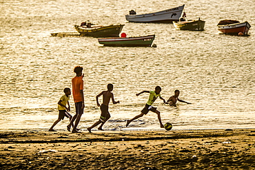 Teenager playing soccer, children, evening mood, city beach of Tarrafal, São Nicolau, Cape Verde, Africa