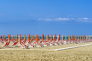 Empty orange deckchairs and sunshades on beach, early season, Viareggio, Tuscany, Italy, Europe