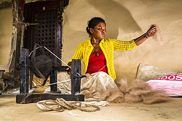 Native woman spinning sheep's wool with traditional spinning wheel in front of house, Ghandruk, Kaski District, Nepal, Asia