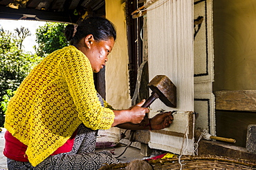 Native woman knotting carpet using sheep's wool in front of house, Ghandruk, Kaski District, Nepal, Asia