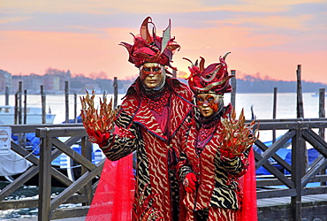 Disguised couple with Venetian masks on the lagoon, carnival in Venice, Italy, Europe