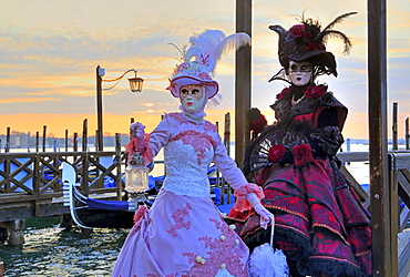 Disguised couple with Venetian masks on the lagoon, carnival in Venice, Italy, Europe