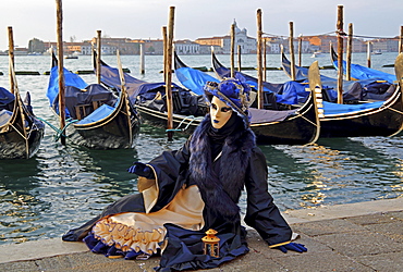 Woman with Venetian mask sitting at the lagoon, behind San Giorgio, carnival in Venice, Venice, Italy, Europe