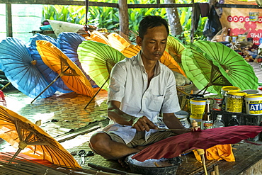 Local man working on multi-colored umbrellas, Pathein, Myanmar, Asia