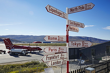 Sign post at the airport with Air Greenland plane on tarmac, Kangerlusuaq, Greenland, North America