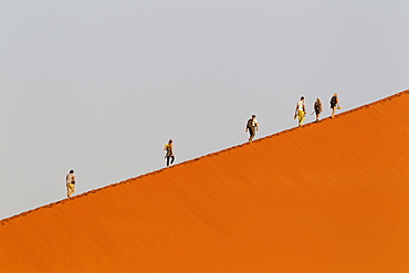 Tourists climbing Dune 45 in the Namib Desert, most likely the world's most photographed and climbed dune, in the evening, Namib-Naukluft National Park, Namibia, Africa