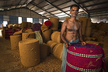 Worker with rolled coconut fibre mats or coir mats, coconut fibre industry, factory, Alappuzha, Kerala, India, Asia