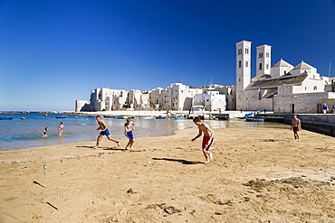 Teenagers playing football onthe beach, harbor, historic centre, Romanesque Old Cathedral, San Corrado and Torrione Passari, Molfetta, Bari Province, Apulia, Italy, Europe