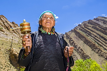 An old Ladakhi woman is turning a prayer wheel, Hemis Gompa, Hemis, Jammu and Kashmir, India, Asia