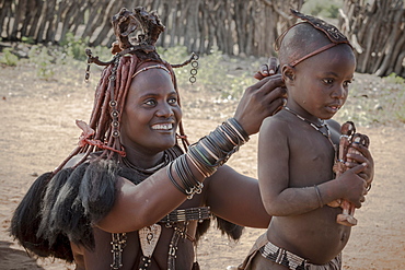 Ovahimba or Himba, a mother puts headdress on her son, Kunene district, Namibia, Africa