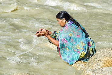 A female pilgrim at the banks of the river Ganges is praying, offering the holy water, Gangotri, Uttarakhand, India, Asia