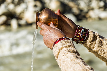 A female pilgrim praying, offering the holy water, at the banks of the river Ganges, Gangotri, Uttarakhand, India, Asia