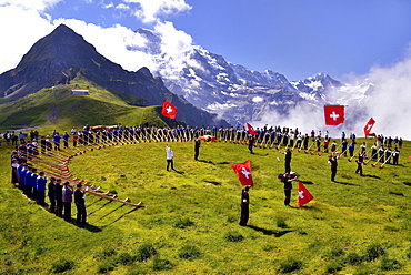 Alphorn blowers and flag throwers, Grosses Alphorntreffen festival, on Mannlichen mountain, Kleine Scheidegg pass, Canton of Bern, Switzerland, Europe