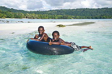 Two boys playing in the clear water, Espiritu Santo, Vanuatu, Oceania