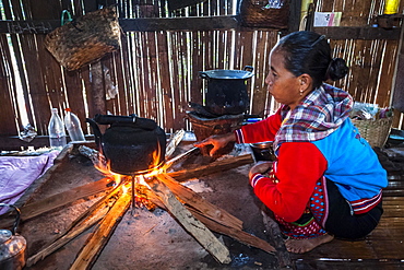 Woman from the Lahu people, hill tribe, ethnic minority, cooking on an open fire in a kitchen made of bamboo, Mae Hong Son Province, Northern Thailand, Thailand, Asia