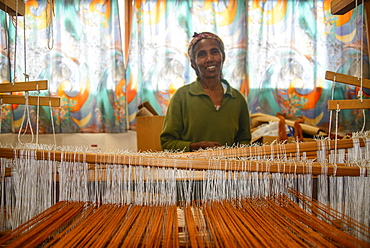 Friendly woman working on a hand weaving loom on social project, Eritrea, Africa