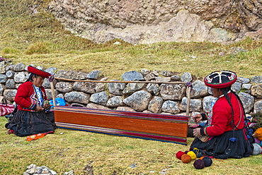 Two elderly women wearing hats, Quechua Indians in traditional dress, squatting on the floor working on the stretcher of a loom, Cinchero, Urubamba Valley, Peru, South America