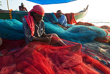 Fishermen repairing fishing nets on the beach, Varkala, Kerala, India, Asia