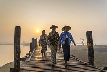 Women wearing traditional hats on a teak bridge, U Bein Bridge over Taungthaman Lake at sunrise, Amarapura, Mandalay Division, Myanmar, Asia