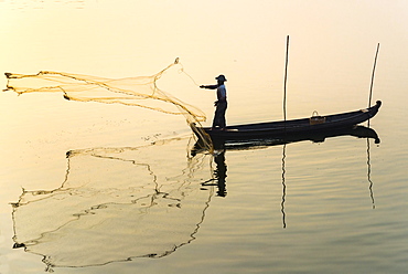 Fisherman in a boat tossing out a net, morning light, Thaungthaman Lake, Amarapura, Mandalay Division, Myanmar, Asia