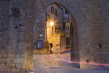 City gate with the light trace of a passing car, Monticchiello, Val d'Orcia region, Province of Siena, Tuscany, Italy, Europe