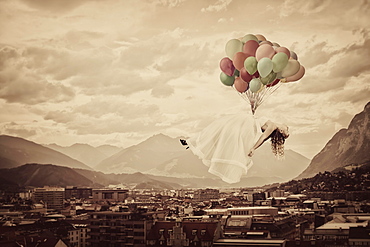 Bride floating on balloons over Innsbruck, Tyrol, Austria, Europe