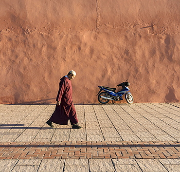 Man walks along red-orange city walls of Marrakech, Morocco, Africa