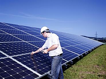 Solar installation technician checking solar panels with a measuring device