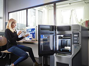 Employee, 25-30 years, checking part of 3D printer in production laboratory, FabLab, Wattens, Tyrol, Austria, Europe