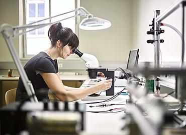 Technician, young woman using electronic microscope